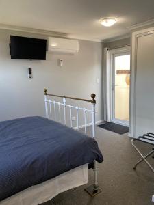 デロレインにあるHeart of Deloraineのベッドと壁にテレビが掛かった寝室