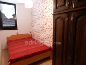 a small bedroom with a red bed and a window at Apartman Dragica in Poreč