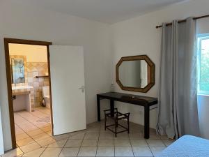a bedroom with a table and a mirror and a bathroom at Tropical Studio in Tamarin +1 photo