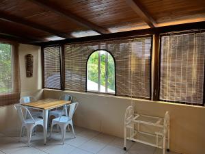 a dining room with a table and chairs and windows at Tropical Studio in Tamarin
