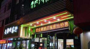 a building with a neon sign on the side of it at Vatica JiangsuJianguo Road Xuanwu Market Hotel in Xuzhou