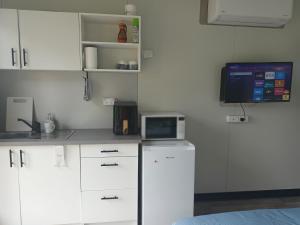 a kitchen with white cabinets and a tv on the wall at Berry World in Timboon