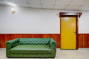 a green couch in a room with a yellow door at Palette Hotel And Resort Garikhana Shillong Formerly Council Lodge in Shillong