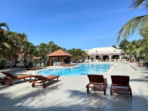 a resort swimming pool with two chairs and a gazebo at Hawaii Resort Phu Quoc in Phu Quoc