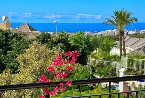 a view of the ocean from a balcony with pink flowers at Sunny terrace & pool in Playa de las Americas