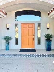 Palm Breezes في رانشو ميراج: باب أمامي برتقالي اللون لمنزل به نبتتان