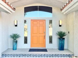 Palm Breezes في رانشو ميراج: باب برتقالي على منزل به نبتتان +70 صورة