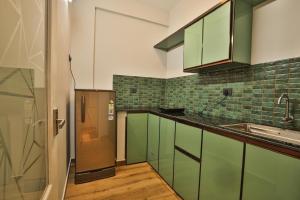 a kitchen with green cabinets and a stainless steel refrigerator at amaze Beach Resort in Varkala