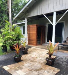 Royal Palm Cottage Hawaii في Hakalau: شرفة منزل به نباتات في الأواني