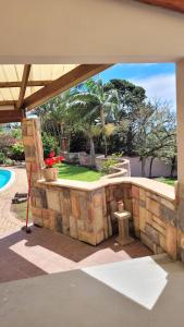 a patio with a stone wall next to a pool at Sharks View in Port Shepstone