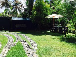 a brick path in the grass with a table and an umbrella at Villa Begonia in Kandy