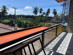 365 Place Maikhao في Ban Mai Salae: مقعد خشبي على شرفة مع أشجار النخيل