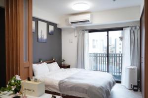 a bedroom with a white bed and a balcony at The Peak Chiyozaki Apartment Hotel in Osaka