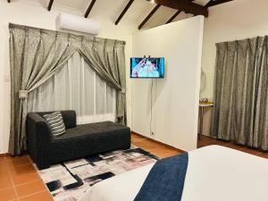 a living room with a couch and a tv on a wall at Alwande's Guesthouse in Richards Bay