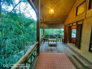 a porch of a house with a bench on it at ติดธารโฮมสเตย์ - Cabin by The stream in Ban Nong Chaeng