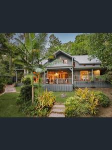 Magnolia Cottage في Cooroy: منزل أمامه نخلة