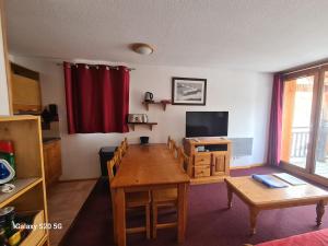 un soggiorno con un tavolo e una televisione di T3 Les Cristallines a Orcières Altre 67 foto