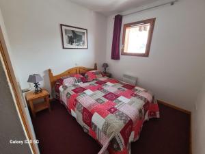 una camera con letto con trapunta e finestra di T3 Les Cristallines a Orcières