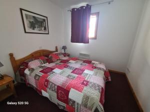 una camera con letto con trapunta e finestra di T3 Les Cristallines a Orcières