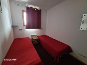 una camera con due letti rossi e una finestra di T3 Les Cristallines a Orcières