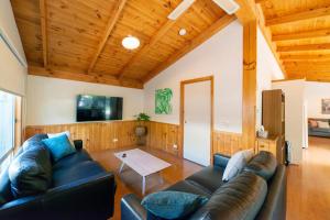 a living room with a leather couch and a tv at Awonga Cottages in Halls Gap