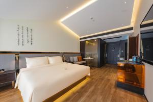 Atour S Hotel Wuxi Nanchang Street في ووشي: غرفة نوم بها سرير أبيض كبير وتلفزيون