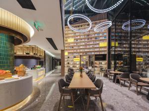 Atour S Hotel Wuxi Nanchang Street في ووشي: مطعم يحتوي على طاولات وكراسي في مبنى