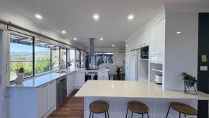 a kitchen with white cabinets and a large window at Station on Pearce in Coffs Harbour