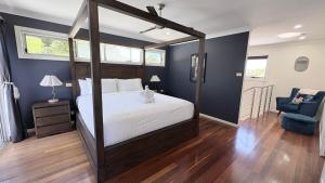 a bedroom with a canopy bed and a blue wall at Station on Pearce in Coffs Harbour