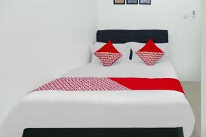 OYO 90609 Mimi & Coco Homestay في Pulau Sembakau Kecil: سرير عليه وسائد حمراء وبيضاء