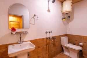 a bathroom with a sink and a toilet and a mirror at Himtrek Stays Katagala in Kasol