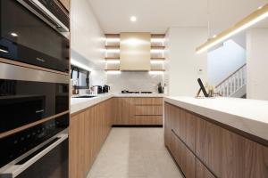 cocina con paredes blancas y armarios de madera en Luxe 3-bedroom Townhouse in Miranda underground parking, en Miranda