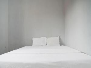 Hotel O Home Stay Syariah Aom Kusman في بلابون راتو: سرير أبيض مع أغطية ووسائد بيضاء