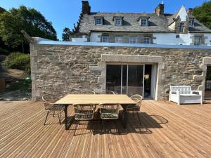 a wooden deck with a table and chairs in front of a building at Moulin entier rénové in Plounéventer
