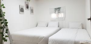 a white bedroom with two beds and a window at Ulsan stay in Ulsan