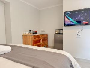 a bedroom with a bed and a flat screen tv on a wall at Berrybliss Guesthouse - Sandton in Sandton