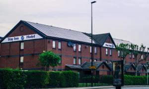 un gran edificio de ladrillo rojo con un cartel. en Stay Inn Manchester en Mánchester