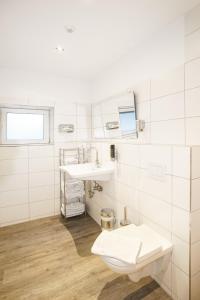 a white bathroom with a toilet and a sink at Landhaus Nütschau in Bad Oldesloe +18 photos
