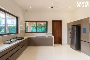 a large kitchen with a sink and a refrigerator at StayVista at Villa Lemonade with BBQ & Bonfire in Alibaug