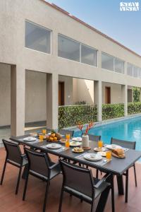 a table with food on it next to a swimming pool at StayVista at Villa Lemonade with BBQ & Bonfire in Alibaug +56 photos