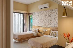a hotel room with two beds and a window at StayVista at Villa Lemonade with BBQ & Bonfire in Alibaug