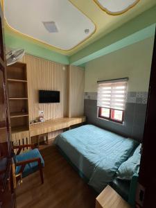 a bedroom with a blue bed and a television at Như Ý Hotel in Kon Plong