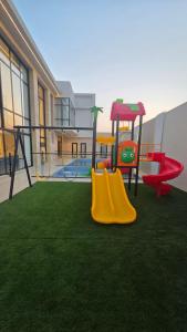 a playground with a slide and a swing at Al Mona Resort 2 شاليه المنى in Al Khobar