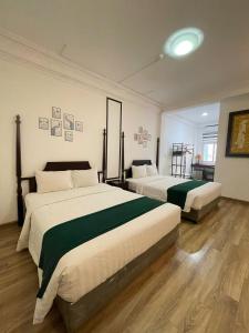 Khách Sạn Thủ Đô Formerly Impressive Hotel في هانوي: غرفة نوم بسريرين بملاءات خضراء وبيضاء +صورة واحدة