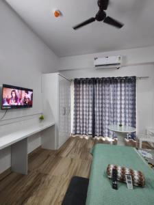 sala de estar con ventilador de techo y TV de pantalla plana en Paramount Luxury Apartment, en Greater Noida