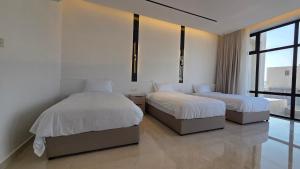 two beds in a room with white walls and windows at Al Mona Resort 2 شاليه المنى in Al Khobar +13 photos
