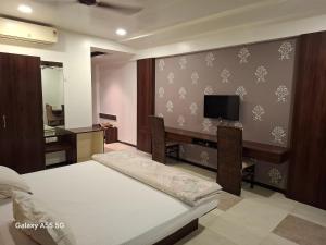 a bedroom with a bed and a desk with a television at Hotel Pride Executive in Satara