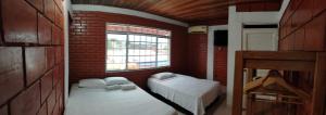 Una habitación con dos camas y una pared de ladrillo. en Leño Verde, en Espinal