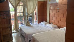 Dos camas en una habitación con una gran ventana. en Leño Verde, en Espinal