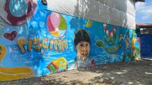 una pintura de un niño al lado de un edificio en Leño Verde, en Espinal